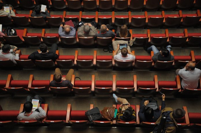 Zdjęcie przedstawia salę konferencyjną, na której siedzą ludzie.