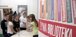 widok na Biblotekę, młodziez sojaca przy stole, czekajaca na zapisy do akcji Zywa Biblioteka