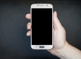 na szarym tele ręka trzymająca biały smartphone